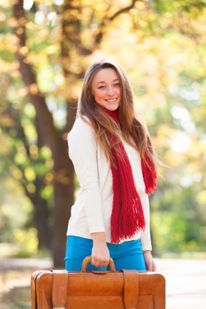 Teen girl with suitcase at autumn outdoorの写真素材
