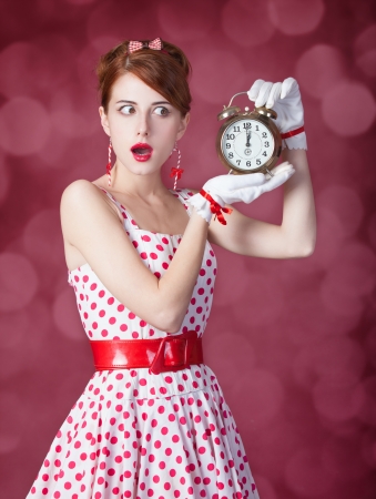 Beautiful redhead women with clock. Photo in retro style with bokeh at background.の写真素材