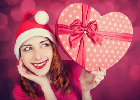 Redhead girl with gifts on red backgroundの写真素材