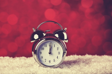 Alarm clock on snow and red background