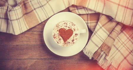 Cup with coffee and shape of the cacao heart on it and scarf. Photo with vintage vignetting.の写真素材