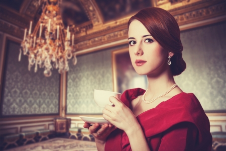 Beautiful redhead women with cup of tea. Photo in old color image style. Beautiful redhead women with cup of tea. Photo in old color image style.
