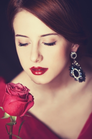 Beautiful redhead women with rose. Photo in old color image style.の写真素材