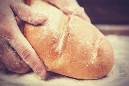 Baker's hands with a bread. Photo with high contrastの写真素材