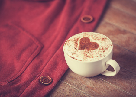 Cup of coffee and red part of clothes. Photo in retro color image style.の写真素材
