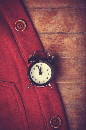 Retro alarm clock and part of clothes. Photo in retro image style.の写真素材