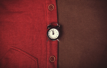Retro alarm clock and part of clothes. Photo in retro image style.の写真素材