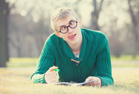 Funny student with pen on a grass