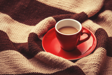 Red cup of the coffee and vintage scarf. Photo with filter as a retro color image style.の写真素材