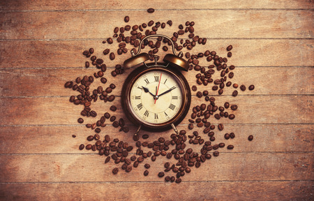 alarm clock and coffee beans on a wooden table. 