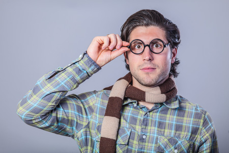 Portrait of funny man in glasses and hearscarf on gray background.の写真素材