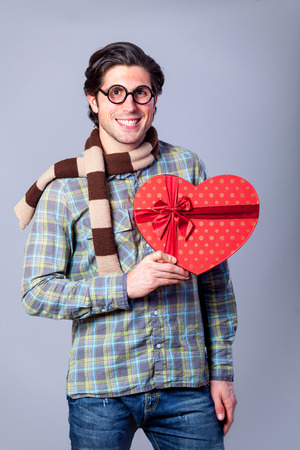 Portrait of funny man in glasses with gift on a gray background.の写真素材