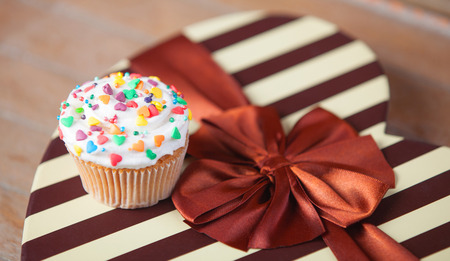 Cream cake with gifts on a wooden table.
