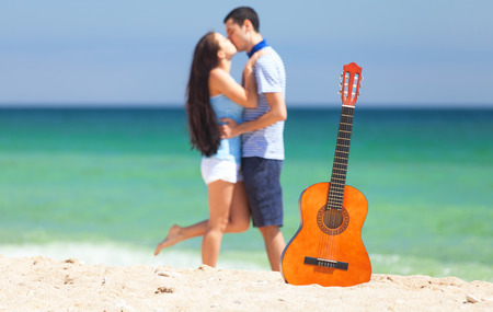 Young couple with guitar on the beach in summer day.の写真素材
