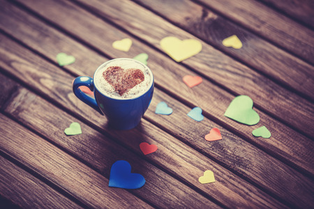 Cup with coffee and heart shape papers on wooden table.の写真素材