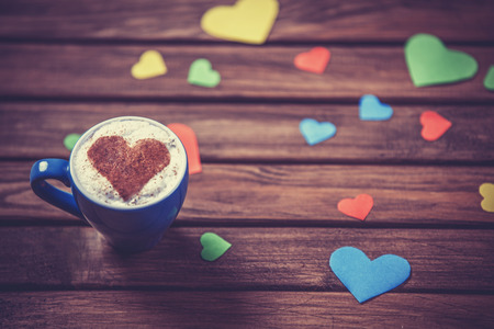 Cup with coffee and heart shape papers on wooden table.の写真素材
