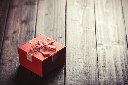 Red gift box on wooden table. Photo in retro color image style.の写真素材