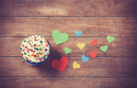 Cupcake and paper hearts on wooden background.の写真素材
