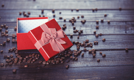 Red gift box and coffee on wooden table. Photo in retro color image style.の写真素材