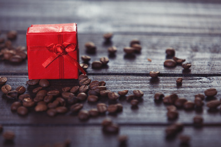 Red gift box and coffee on wooden table. Photo in retro color image style.の写真素材