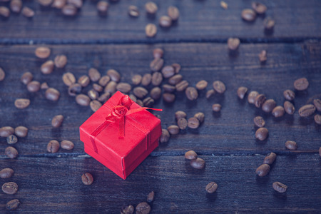 Red gift box and coffee on wooden table. Photo in retro color image style.の写真素材