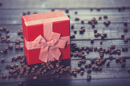 Red gift box and coffee on wooden table. Photo in retro color image style.の写真素材