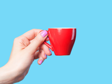 Hand holding red cup on blue backgroundの写真素材