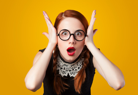 Surprised redhead girl on yellow background.の写真素材