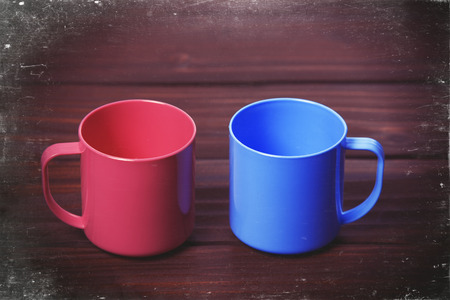 Two color cups on woodent table. Photo in old color image style.の写真素材