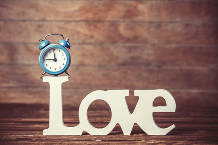 Alarm clock and word Love on wooden table.の写真素材