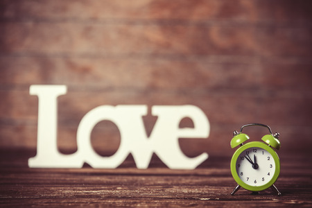 Clock with word love on wooden table.の写真素材