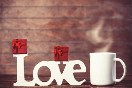 Cup of coffee, gift and word Love on wooden table.の写真素材