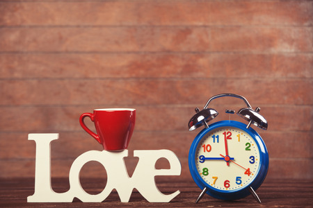 Word Love, cup and alarm clock on wooden table.の写真素材
