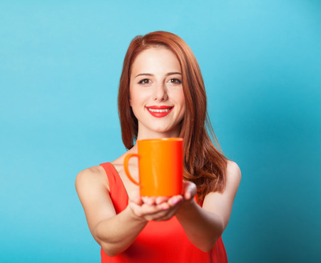 Redhead women with cup on blue background.の写真素材