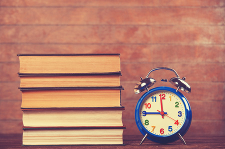 Alarm clock and books on wooden table.の写真素材