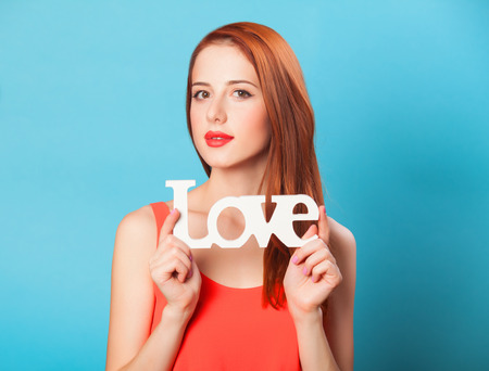 Happy redhead women with word Love on blue background.の写真素材