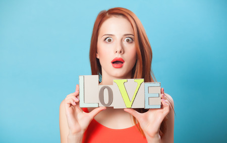 Surprised redhead women with word Love on blue background.の写真素材
