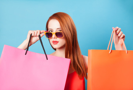 Style redhead women holding shopping bags on blue background.の写真素材