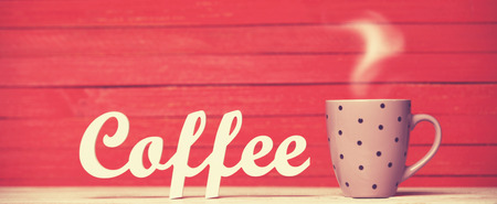 Abstract wooden word Coffee with cup on red wooden background.の写真素材