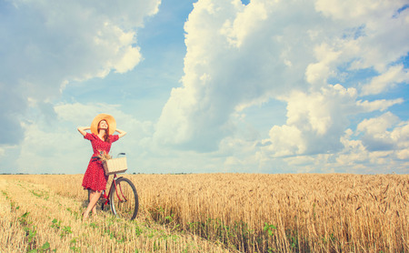 Redhead peasant girl with bicycle on wheat field.の写真素材