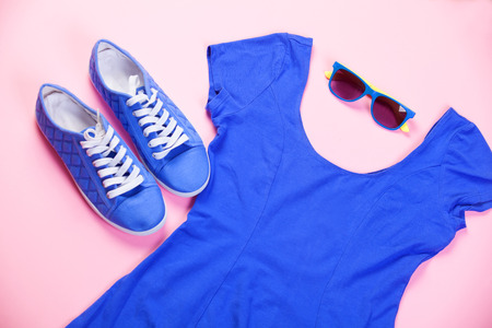Gumshoes, sunglasses and dress on pink background.の写真素材