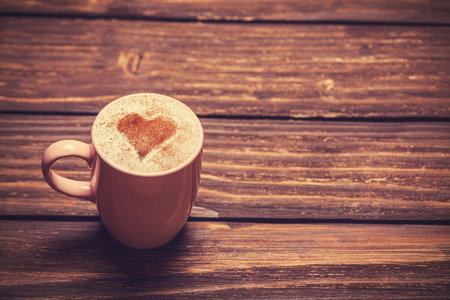 Cup of coffee with shape heart on wooden table.の写真素材