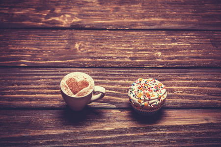 Cup of coffee and cupcake on wooden table.の写真素材