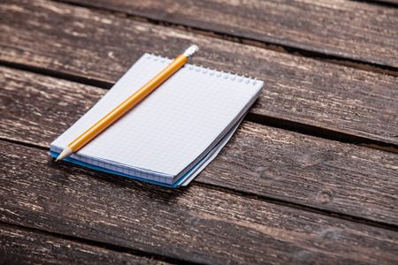 Notebook and pencil on wooden table.