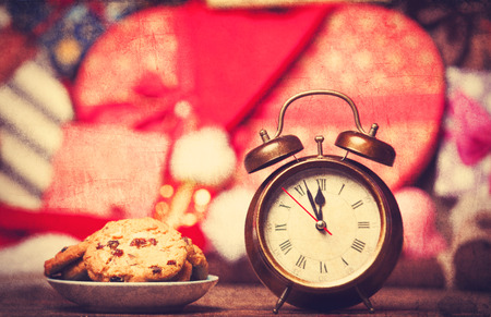 Retro alarm clock with cookie on a table. Photo in retro color image styleの写真素材