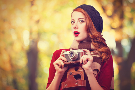 Redhead women in beret with camera in the parkの写真素材