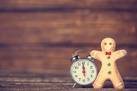 Cookie man and retro alarm clock on wooden background