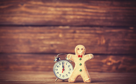 Cookie man and retro alarm clock on wooden background