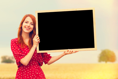 Redhead girl with blackboard at wheat fieldの写真素材