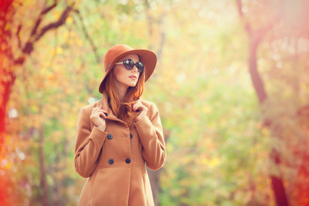 Redhead girl in sunglasses and hat in the autumn park.の写真素材